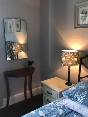a bedroom with a bed and a table with a lamp at Netherdene Country House Bed & Breakfast in Troutbeck