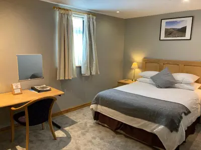a bedroom with a bed and a desk and a window at Washington Central Hotel and Sleepwell Inn in Workington