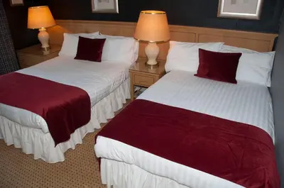 two beds in a hotel room with red and white sheets at Caledonian Hotel in Dumfries