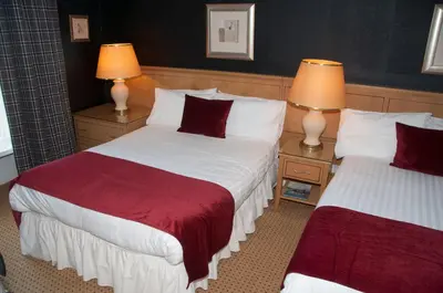 a hotel room with two beds and two lamps at Caledonian Hotel in Dumfries