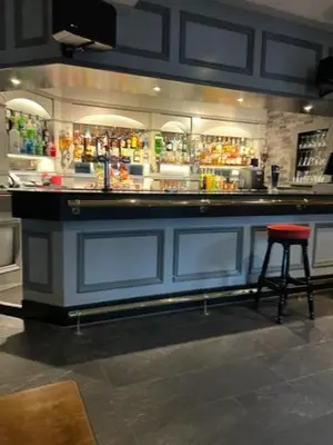 a bar with a red stool in front of it at Caledonian Hotel in Dumfries