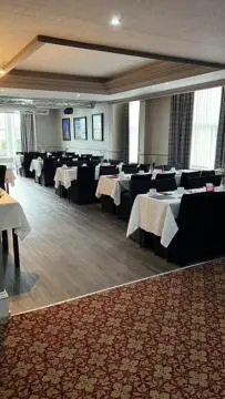 a banquet hall with white tables and black chairs at Caledonian Hotel in Dumfries