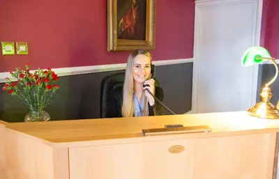 a woman talking on a phone at a desk at Caledonian Hotel in Dumfries