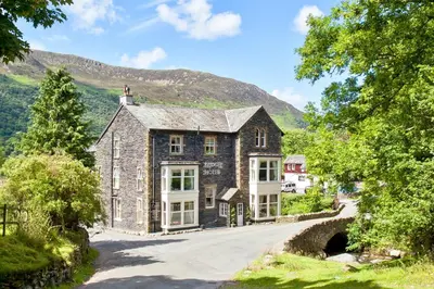 an old stone house on a road in the mountains at Bridge Hotel in Buttermere