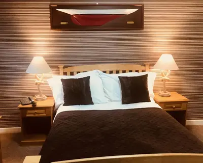 a bedroom with a large bed with two lamps on tables at Creebridge House Hotel in Newton Stewart
