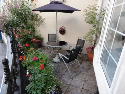 a patio with a table and chairs and flowers at Edelweiss Guest House in Douglas