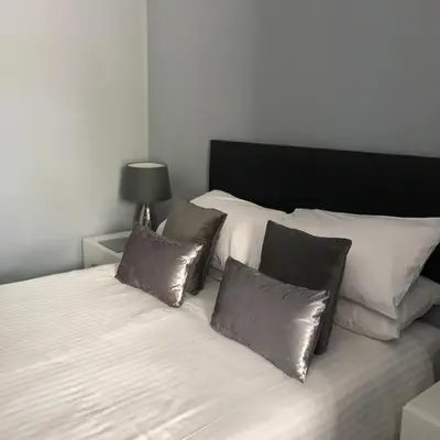 a white bed with four pillows on top of it at Edelweiss Guest House in Douglas