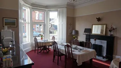 a dining room with a table and chairs and windows at Lindean Guest House in Dumfries