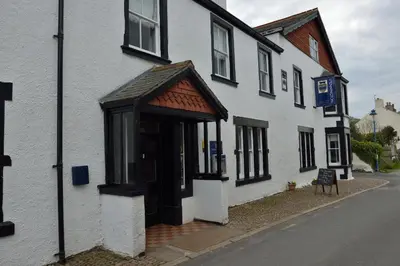 a white building with an open door on a street at The Pennington Hotel in Ravenglass