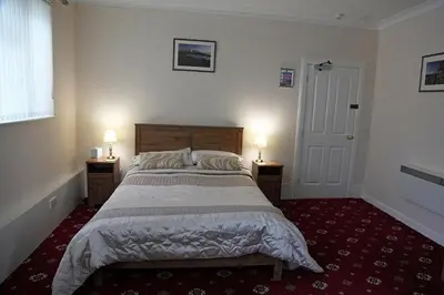 a bedroom with a large bed and two lamps on tables at Balmoral Hotel in Moffat