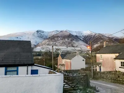 a village with snow covered mountains in the background at Katellen Cottage in Threlkeld