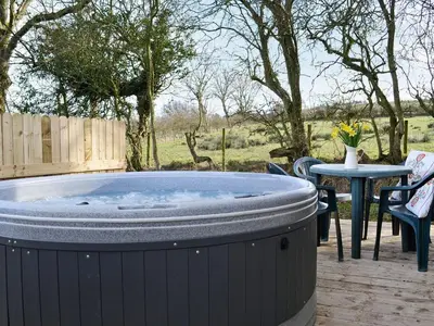 a hot tub on a deck with a table and chairs at Kestrel Cabin - Uk1246 in Westward