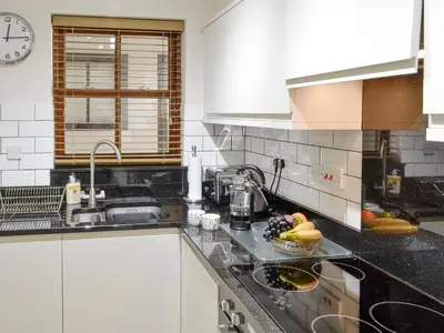 a kitchen with white cabinets and a black counter top at High Views in Keswick