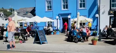 a group of people sitting outside of a blue building at The Waterfront in Portpatrick
