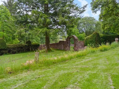 an old stone building with a tree in a field at The Old Stables in Sorn