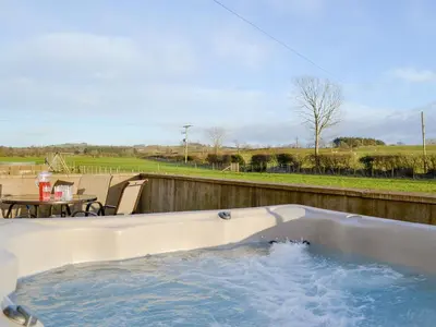 a jacuzzi tub on a patio with a table at Little Meadow in Dearham