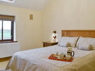 a bedroom with a bed with a tray of food on it at Little Meadow in Dearham