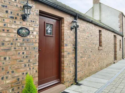 a brick building with a brown door on it at The Old Byre in Dearham