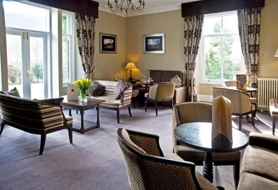 a living room with chairs and tables and windows at New Dungeon Ghyll Hotel in Great Langdale