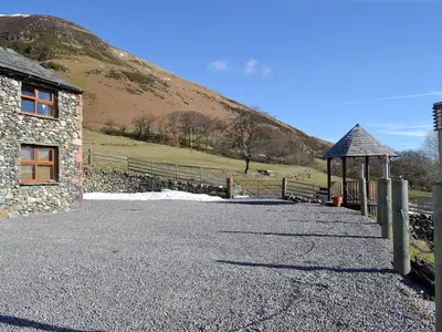 a stone building with a gazebo next to a hill at Lucy's Lodge - Uk1260 in Threlkeld