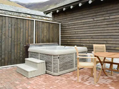 a hot tub on a patio with a table and chair at Lucy's Lodge - Uk1260 in Threlkeld