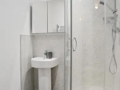 a white bathroom with a sink and a shower at Gilbert's Warrant in Keswick