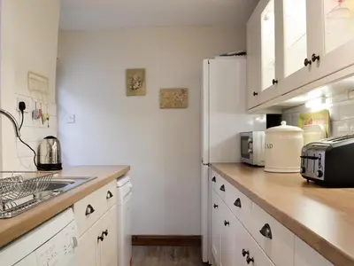a kitchen with white cabinets and a white refrigerator at The Tottsie in Bassenthwaite
