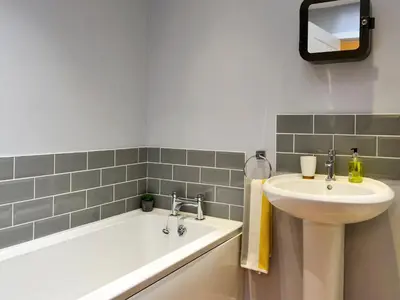 a bathroom with a sink and a bath tub at Porthole Cottage in Allonby