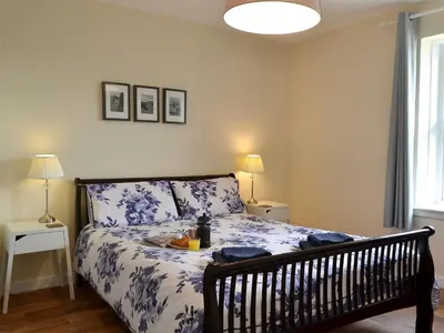 a bedroom with a bed with blue and white sheets at Porthole Cottage in Allonby