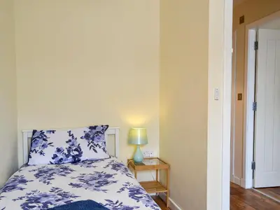 a bedroom with a blue and white bed and a lamp at Porthole Cottage in Allonby