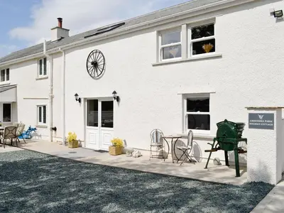 a white building with a patio with chairs and a clock at Greengill Farm Holiday Cottage - Ukc2768 in Gilcrux