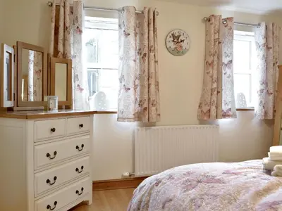 a bedroom with a bed and a dresser and windows at The Costins in Allonby