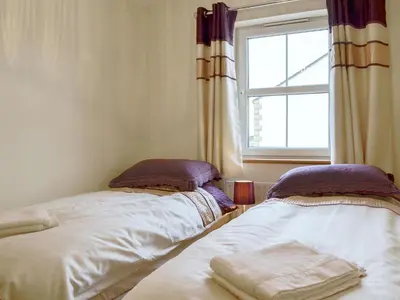 two beds in a room with a window at The Costins in Allonby