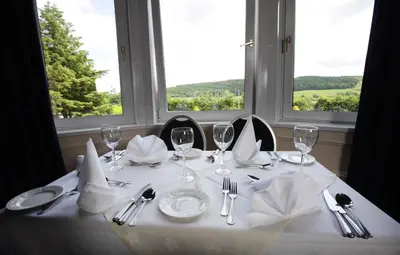 a dining table with a white table cloth and glasses at Cressfield Country House Hotel in Ecclefechan