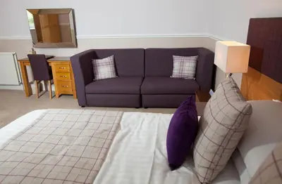 a bedroom with a couch and a bed with purple pillows at Cressfield Country House Hotel in Ecclefechan