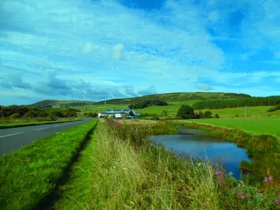 a road in the middle of a field with a river at Rhins of Galloway in Cairnryan