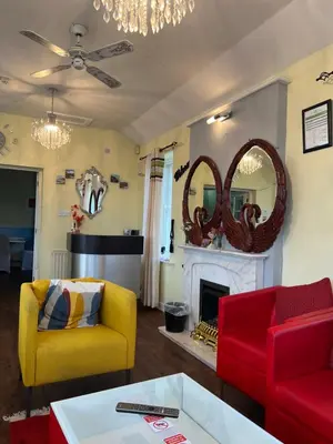 a living room with red and yellow chairs and a fireplace at Lynebank House Hotel, Bed & Breakfast in Carlisle