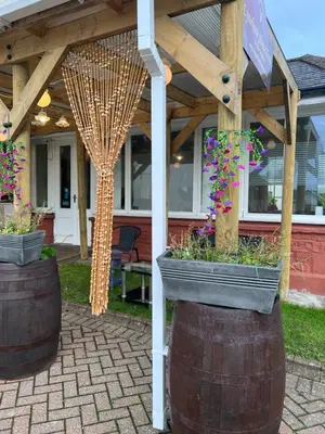 a patio with two large barrels with flowers in them at Lynebank House Hotel, Bed & Breakfast in Carlisle