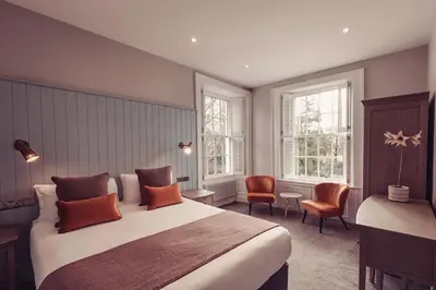 a bedroom with a large bed and two windows at Tweedies Bar and Lodge in Grasmere