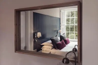 a mirror on a wall with a bed in a room at Tweedies Bar and Lodge in Grasmere