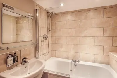 a bathroom with a white tub and a sink at Tweedies Bar and Lodge in Grasmere
