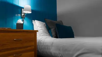a bedroom with a bed and a blue wall at Tweedies Bar and Lodge in Grasmere