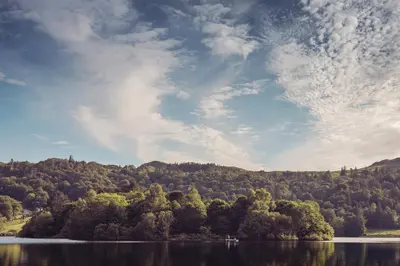 a view of a lake with trees on a hill at Tweedies Bar and Lodge in Grasmere