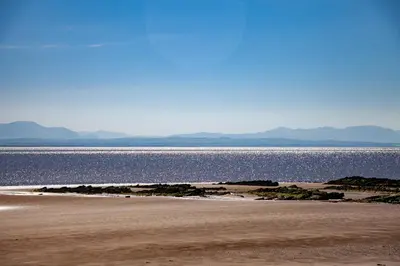a beach with the ocean and mountains in the background at Shore Cottage in Dumfries