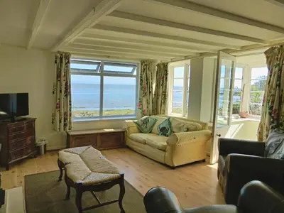 a living room with a couch and a view of the ocean at Shore Cottage in Dumfries