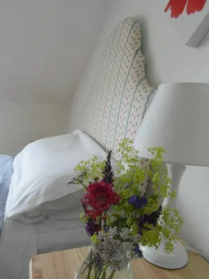 a vase of flowers on a table next to a bed at Powillimount Cottage in Kirkbean