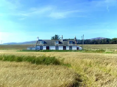 a white house in the middle of a field at Powillimount Cottage in Kirkbean