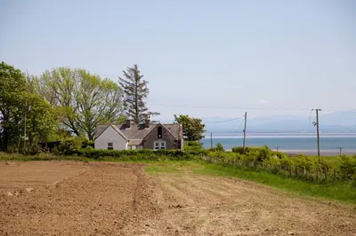 a house on the side of a dirt road at West Lodge in Kirkbean