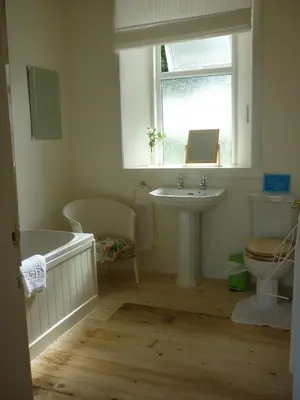 a bathroom with a tub and a sink and a window at West Lodge in Kirkbean
