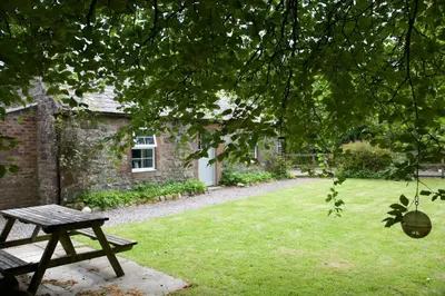 a picnic table in front of a stone house at Little Dunbar Cottage in Kirkbean